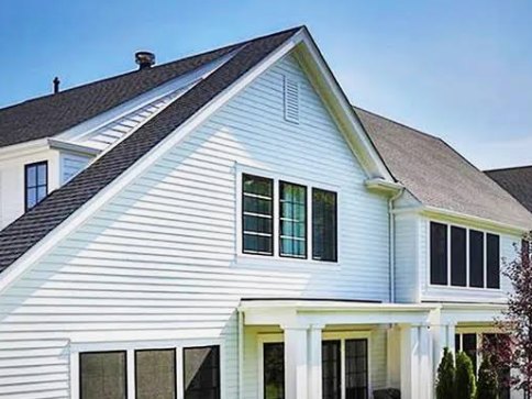 A white clapboard house with a covered porch on a clear sunny day, sealed and insulated