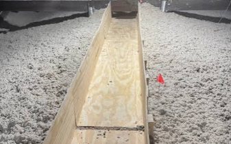 Blown-in cellulose insulation covering an attic floor beside a plywood walkway